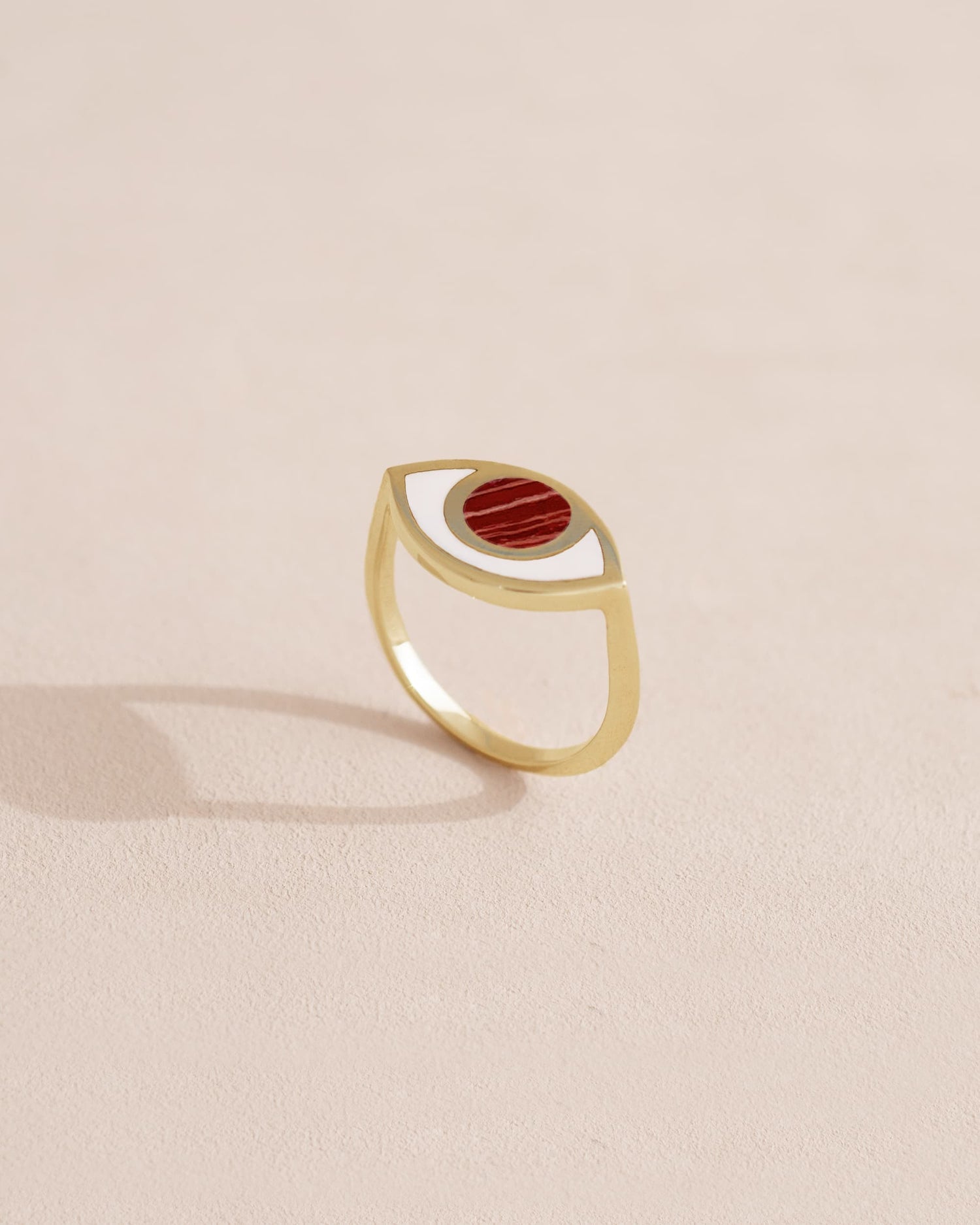 Gold ring with red stone on a light beige background