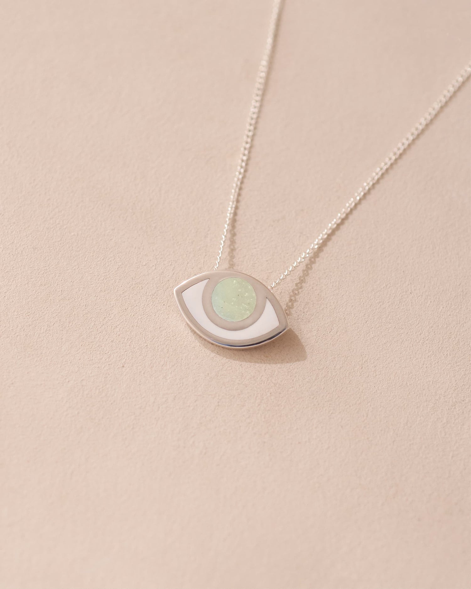 A silver pendant necklace with a round opal stone set in a eye-shaped frame, displayed against a light background.