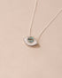 A silver pendant necklace with a labradorite stone in the shape of an eye, displayed against a light background.