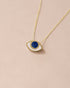 A 14K yellow gold pendant necklace with a lapis lazuli stone shaped as an eye, displayed against a light background.