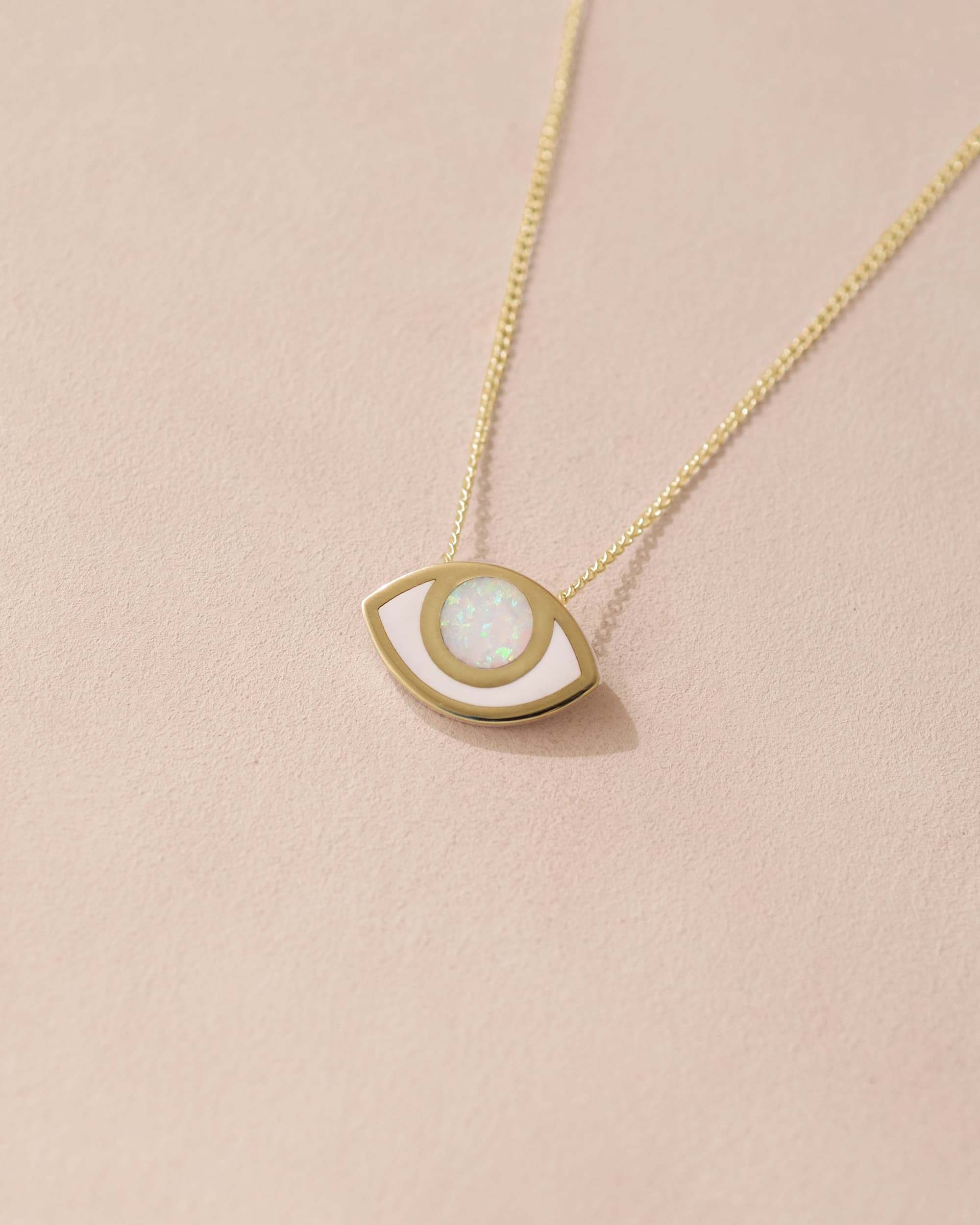 A 14K yellow gold pendant necklace with an eye-shaped design made of opal, displayed against a light background.
