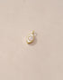 A small mother of pearl charm with a gold setting, shaped like a simple eye, placed on a beige background.