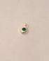 A small 14K yellow gold charm with a malachite stone shaped like an eye, placed on a light background.