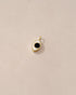 A small onyx stone set in a gold charm resembling an eye, placed against a beige background.