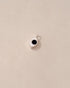 A small silver charm with an onyx stone shaped like an eye, displayed against a beige background.