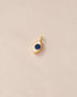 gold charm shaped like an eye with lapis lazuli center