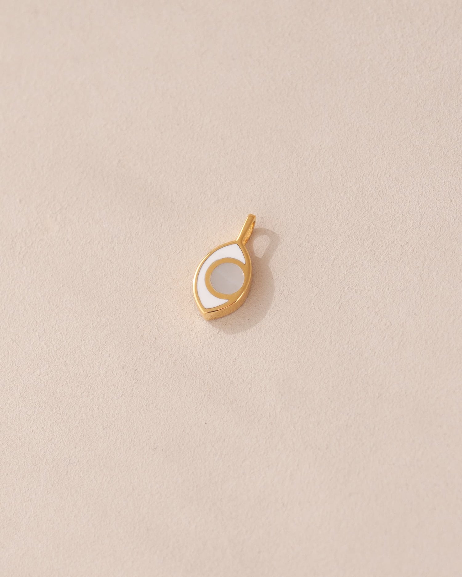 gold charm shaped like an eye with mother of pearl center