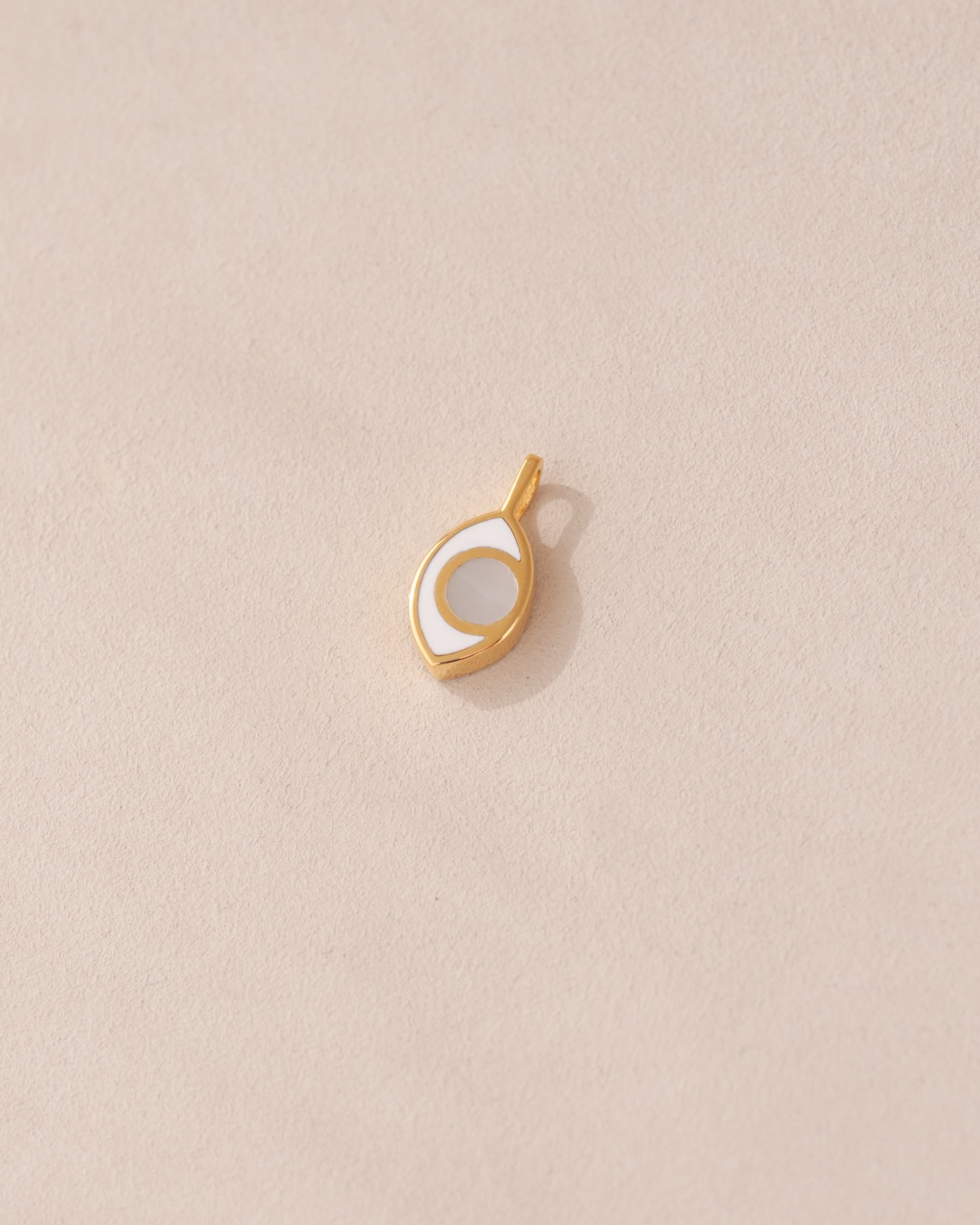 gold charm shaped like an eye with mother of pearl center