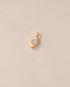 gold charm shaped like an eye with mother of pearl center
