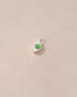 Small round earring with green gemstone on a light beige background
