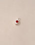 A silver charm with a carnelian stone in the shape of a small eye on a light background.