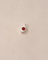 A small silver charm with a jasper stone in the shape of an eye, placed on a light background.