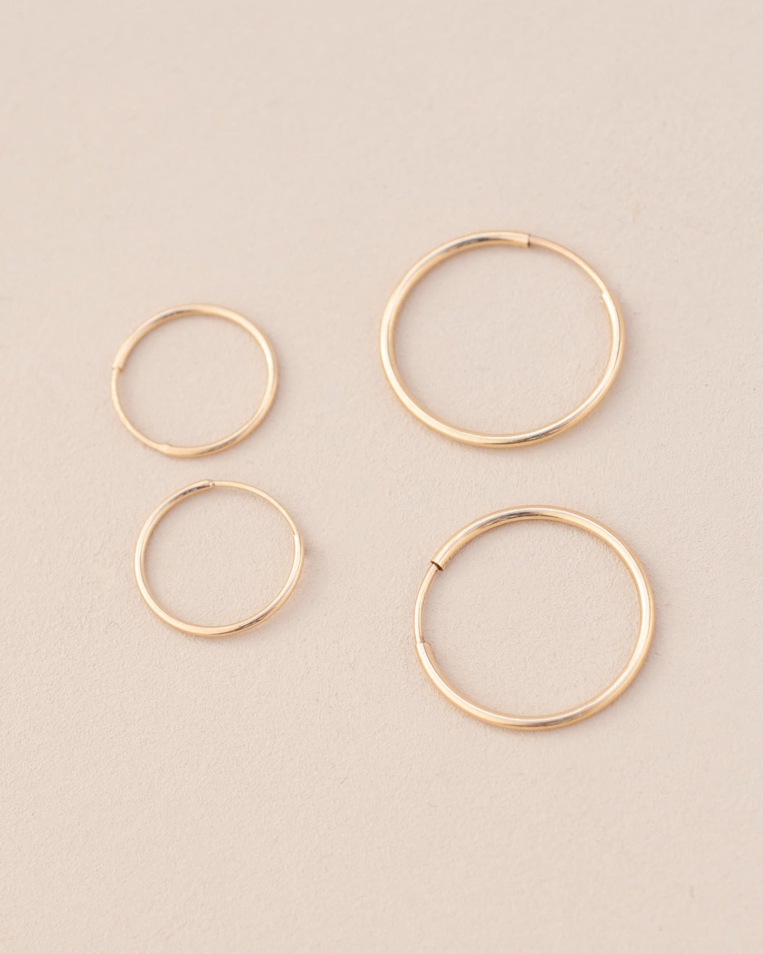four gold hoops on neutral background