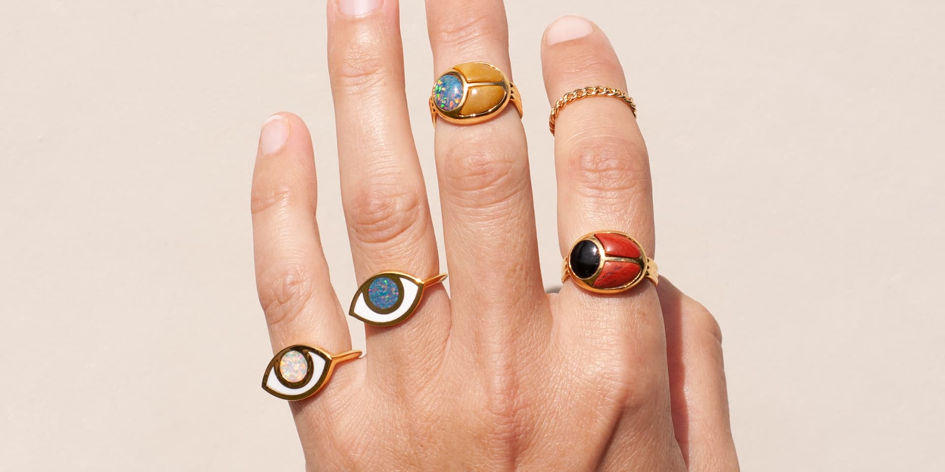 a close up of a hand wearing multiple gold rings inlayed with different stones