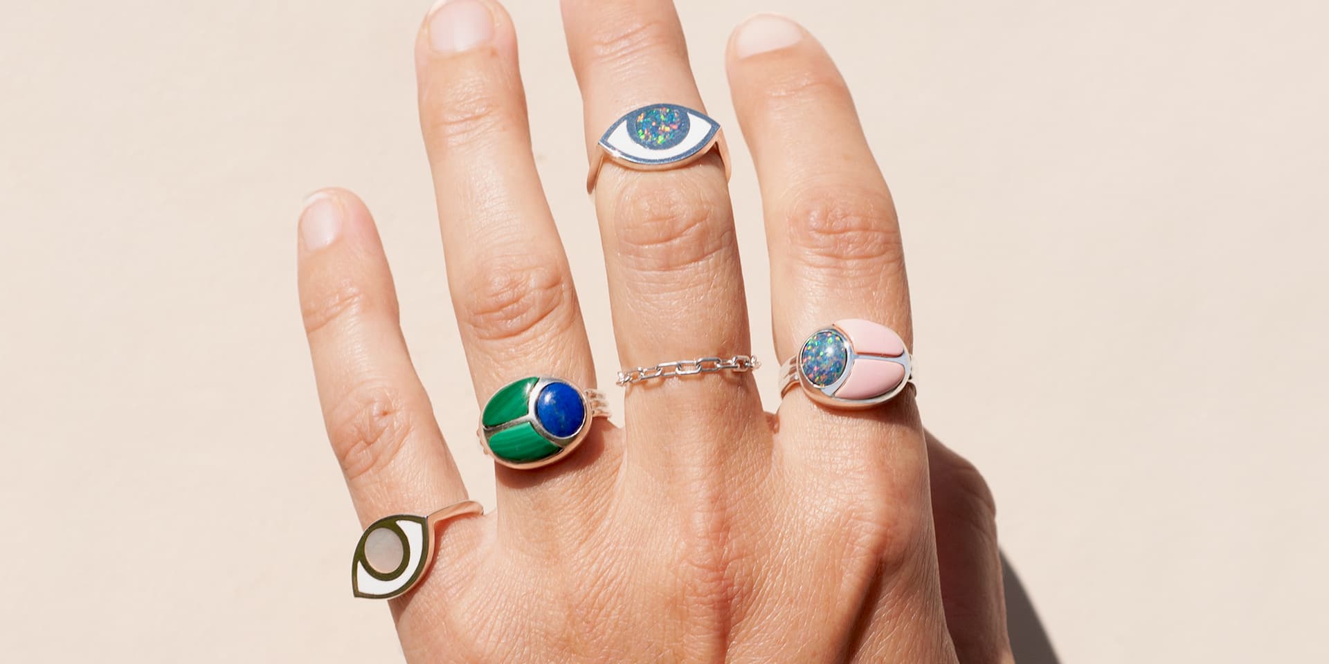a close up of a hand wearing multiple silver rings inlayed with different stones