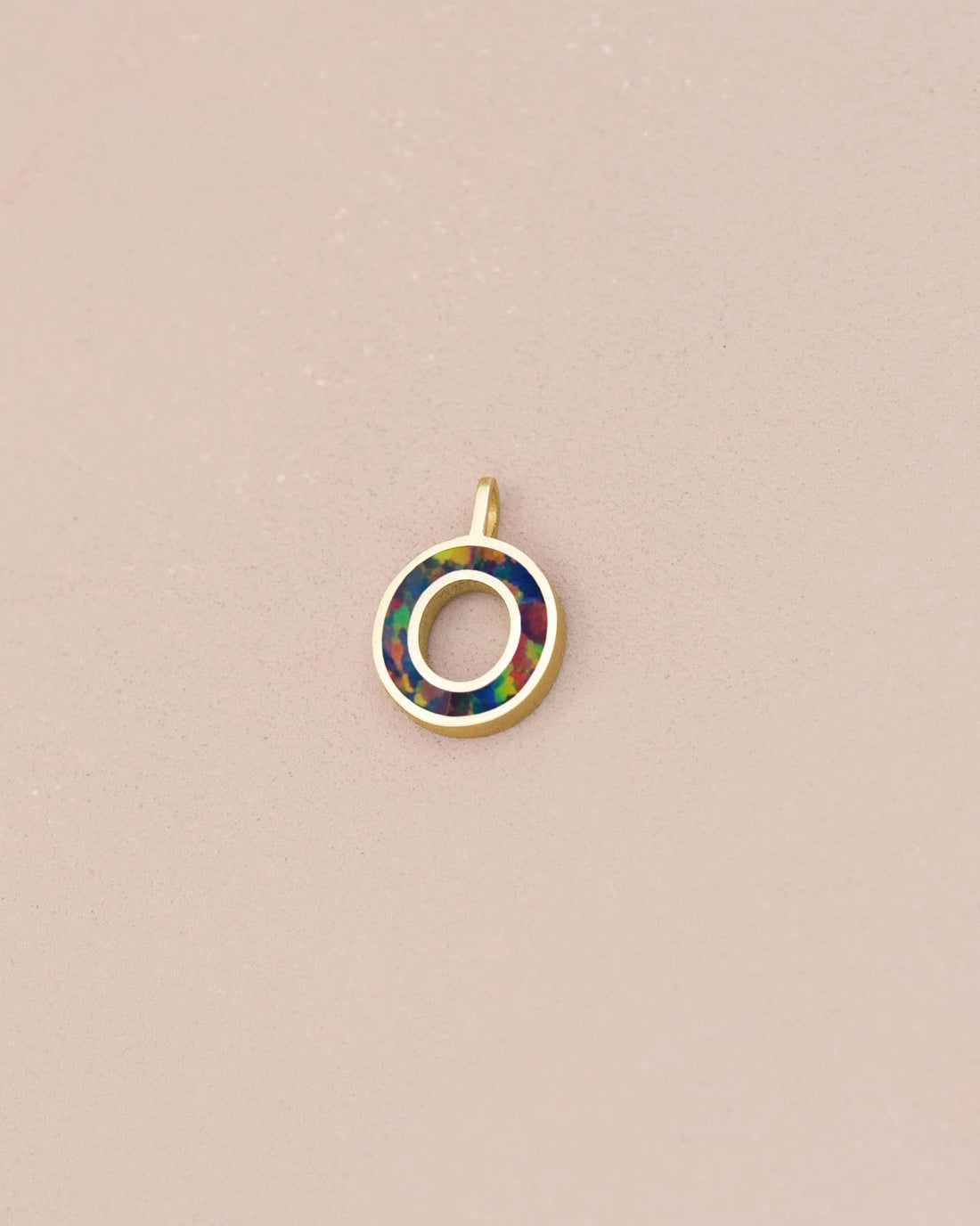 Jewelry pendant with multicolored circle design on a beige background