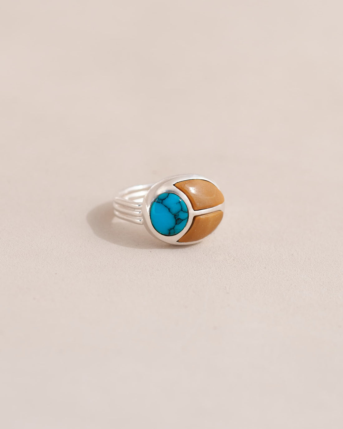 A silver ring featuring a scarab design with turquoise and yellow opal inlays, displayed against a neutral background.