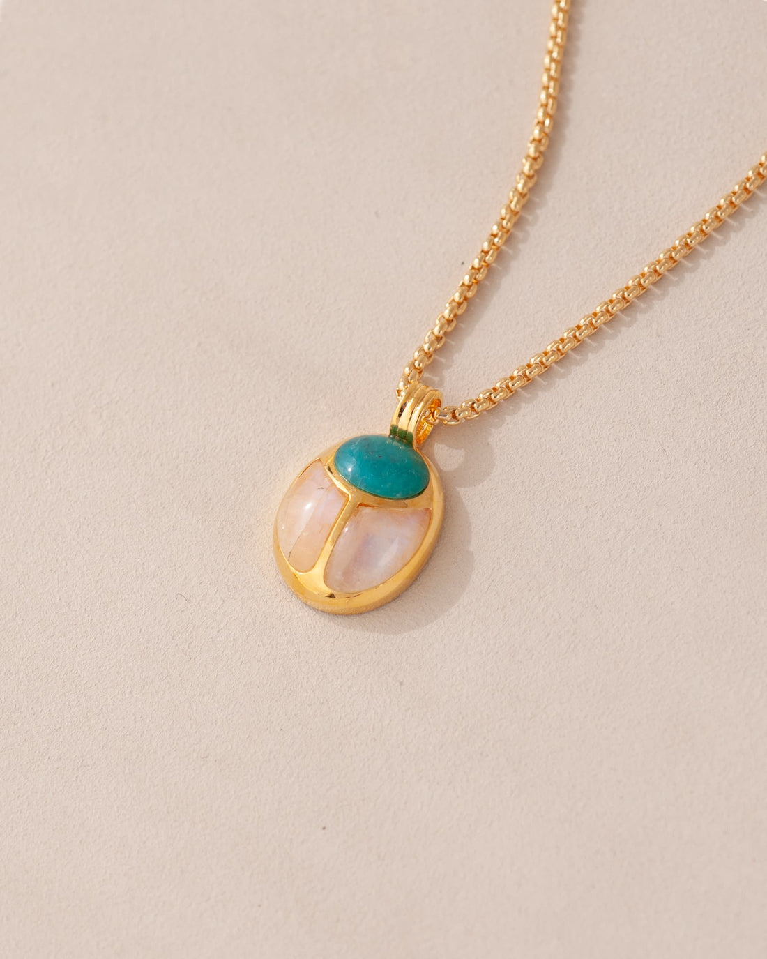 A one-of-a-kind SunRa Medal featuring chrysocolla and moonstone inlays, vermeil-coated in gold, attached to a gold-colored snake chain with a lobster clasp.