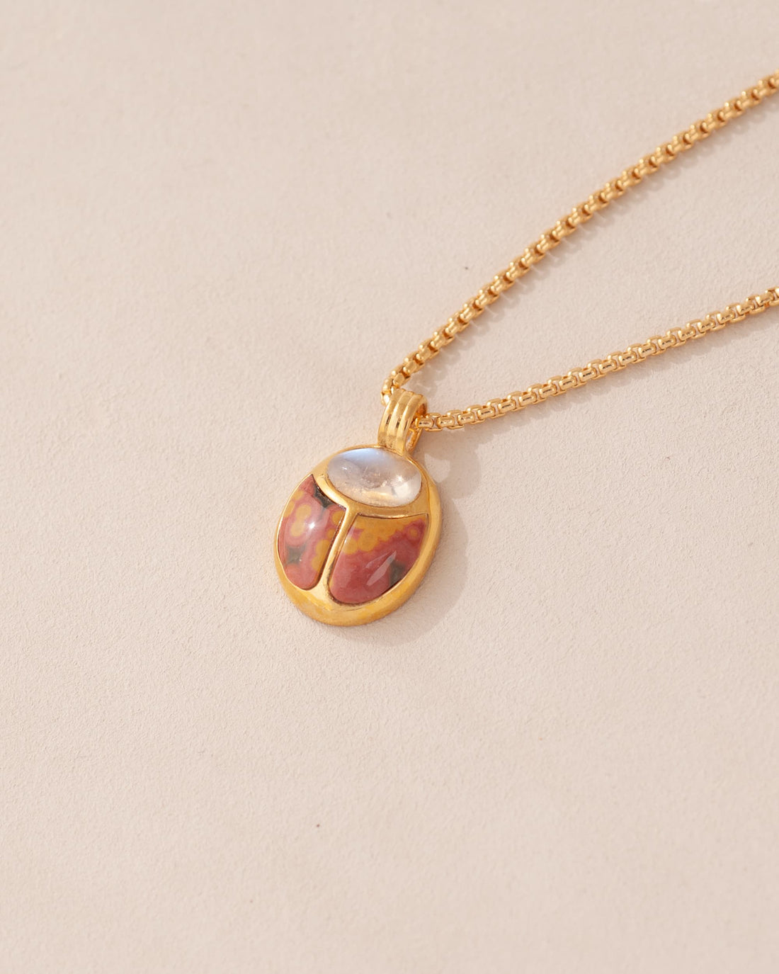 A one-of-a-kind SunRa Medal with moonstone and ocean jasper inlays, vermeil-plated, displayed on a gold-toned snake chain with a lobster clasp.