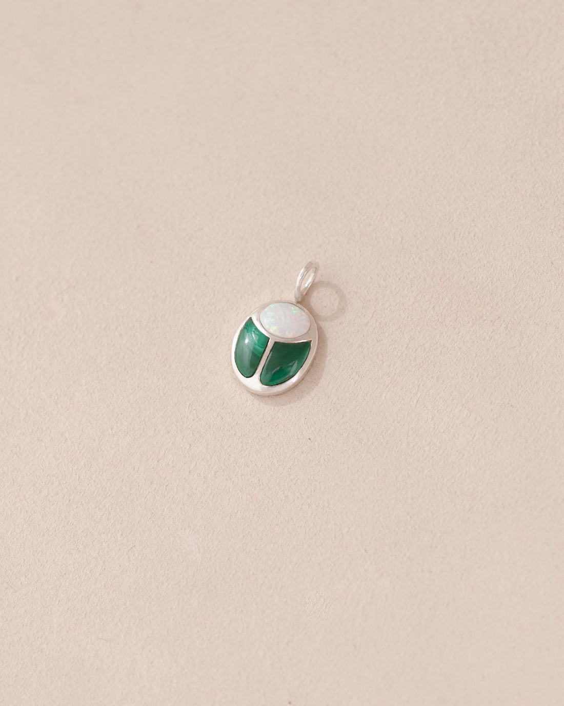 A silver charm featuring a miniature scarab amulet design with jelly opal and malachite inlay, displayed against a neutral background.