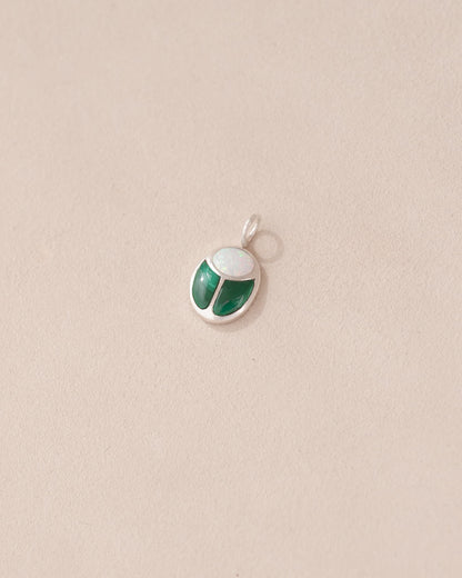 A silver charm featuring a miniature scarab amulet design with jelly opal and malachite inlay, displayed against a neutral background.