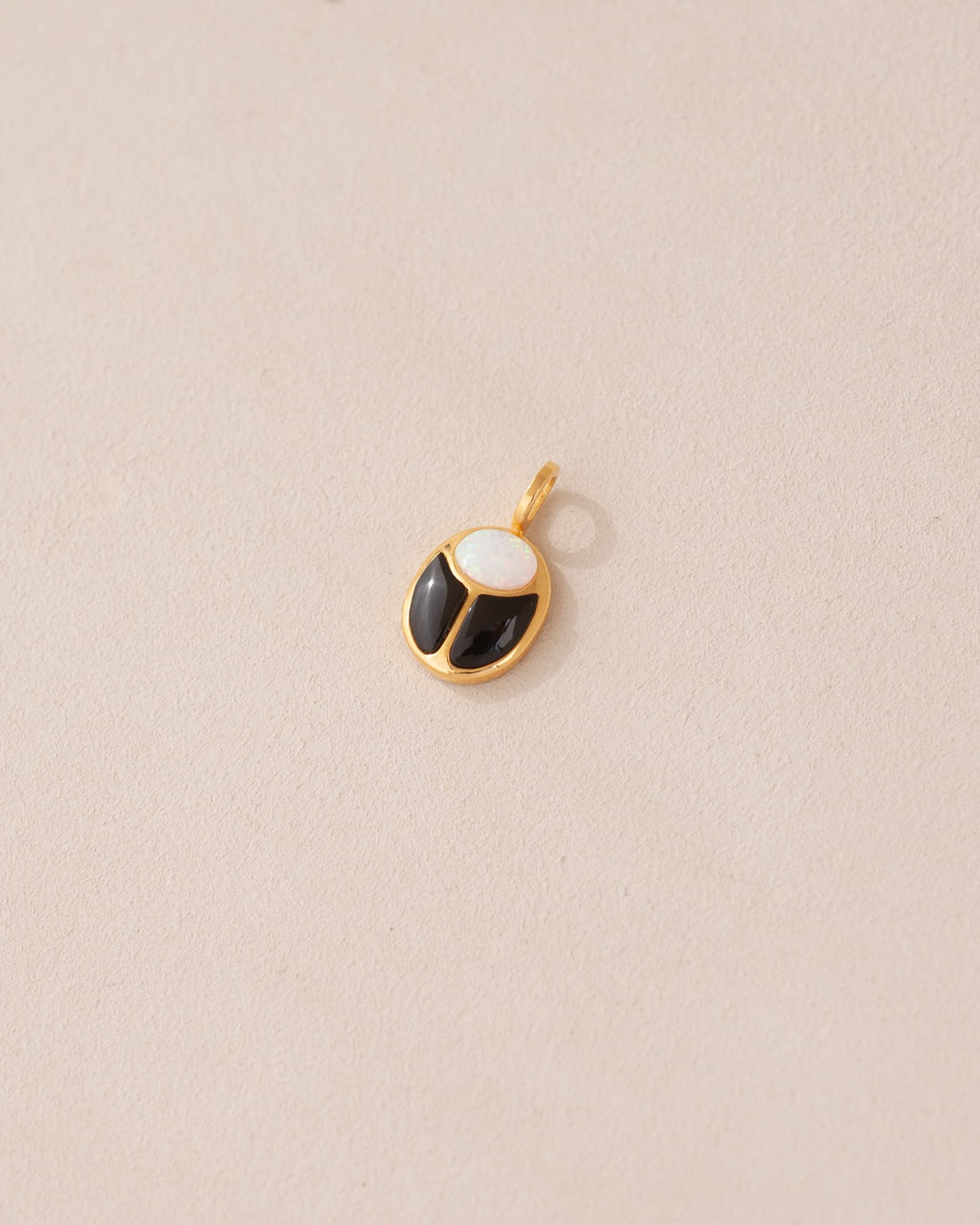 A small gold charm featuring a black and white opal scarab design.