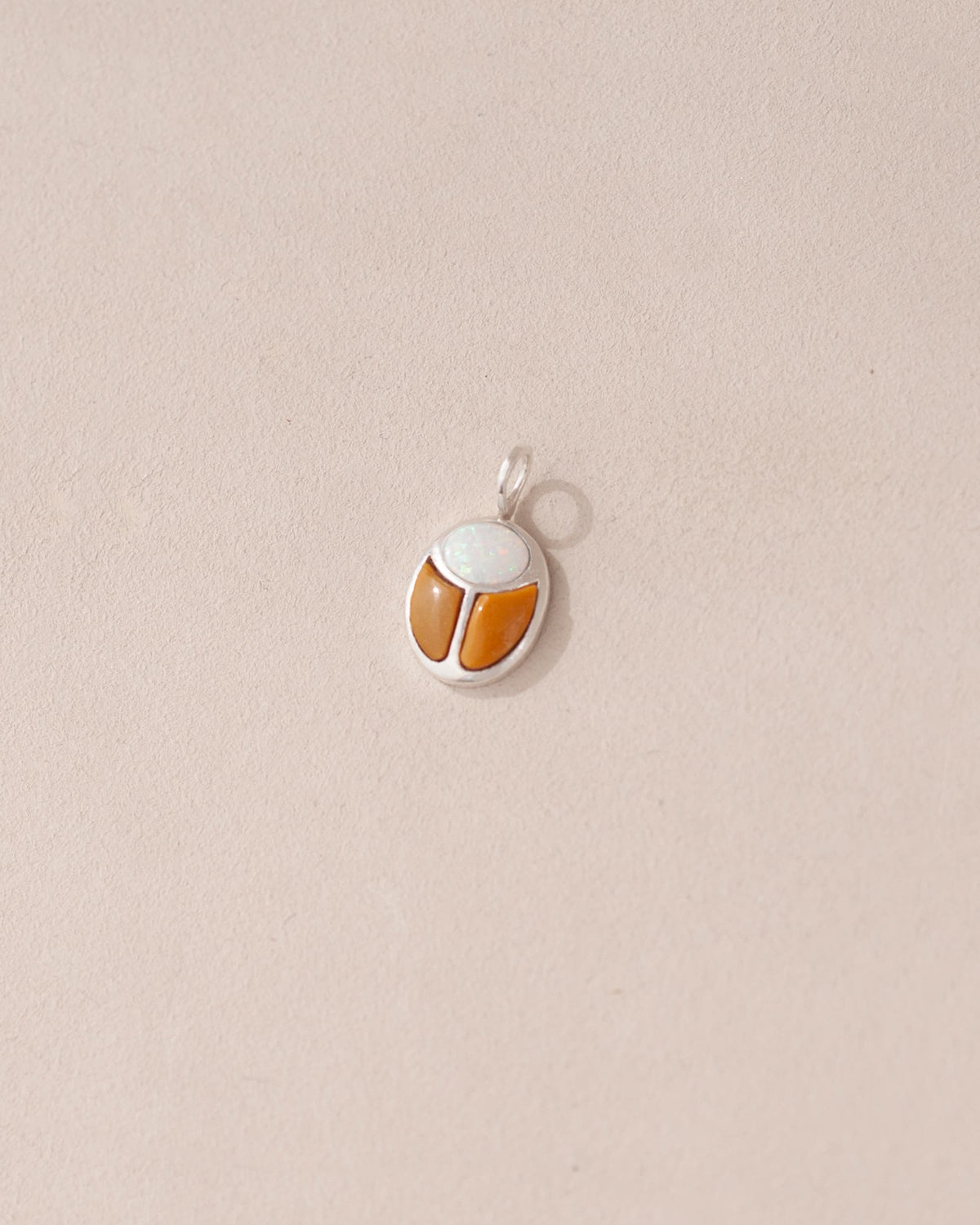 A silver charm featuring a scarab design with jelly opal and mookaite stones on a light background.
