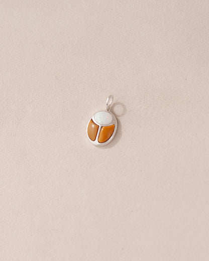 A silver charm featuring a scarab design with jelly opal and mookaite stones on a light background.