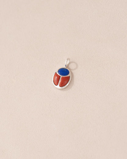 A silver-colored charm with a lapis lazuli and red jasper design, attached to a small silver chain.