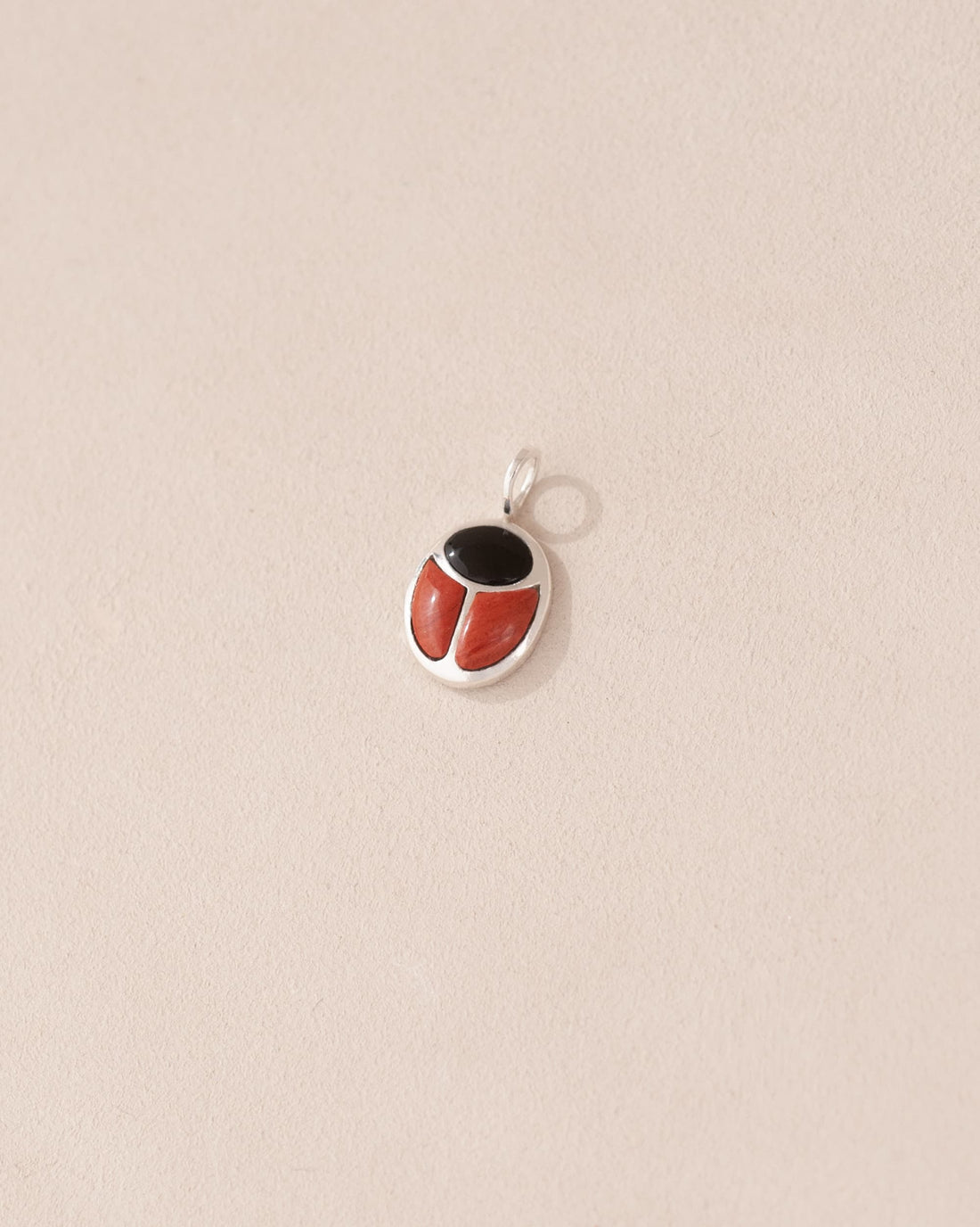 A silver-colored charm with an onyx and red jasper design, intended for use as a talisman.