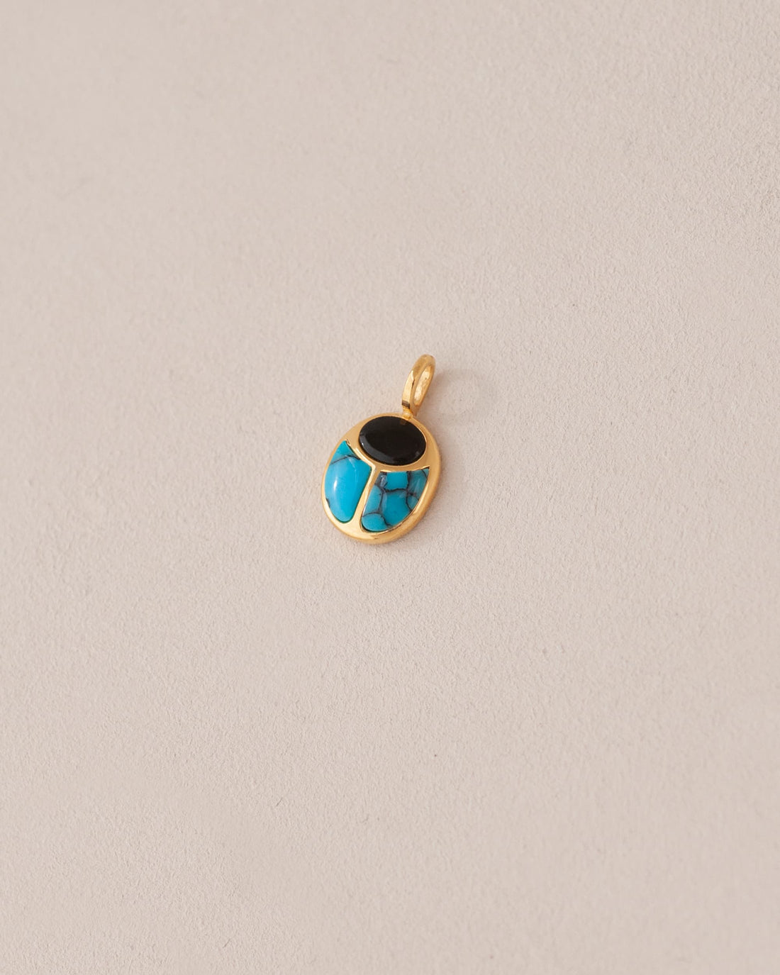 A 14K yellow gold charm featuring a scarab design with onyx and turquoise inlay, displayed against a neutral background.