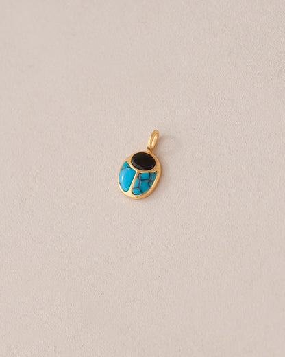 A 14K yellow gold charm featuring a scarab design with onyx and turquoise inlay, displayed against a neutral background.