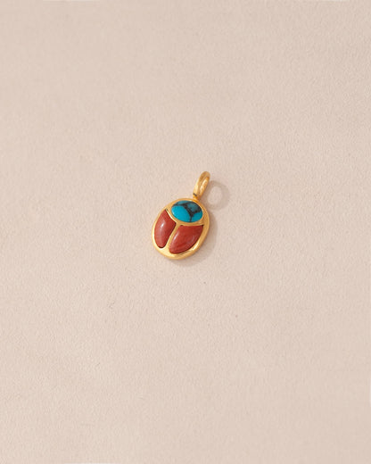 A 14K yellow gold charm featuring a turquoise and red jasper scarab design.
