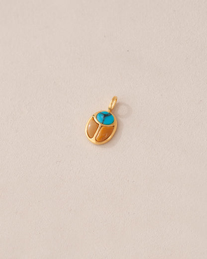 A 14K yellow gold charm in the shape of a scarab amulet with turquoise detailing.