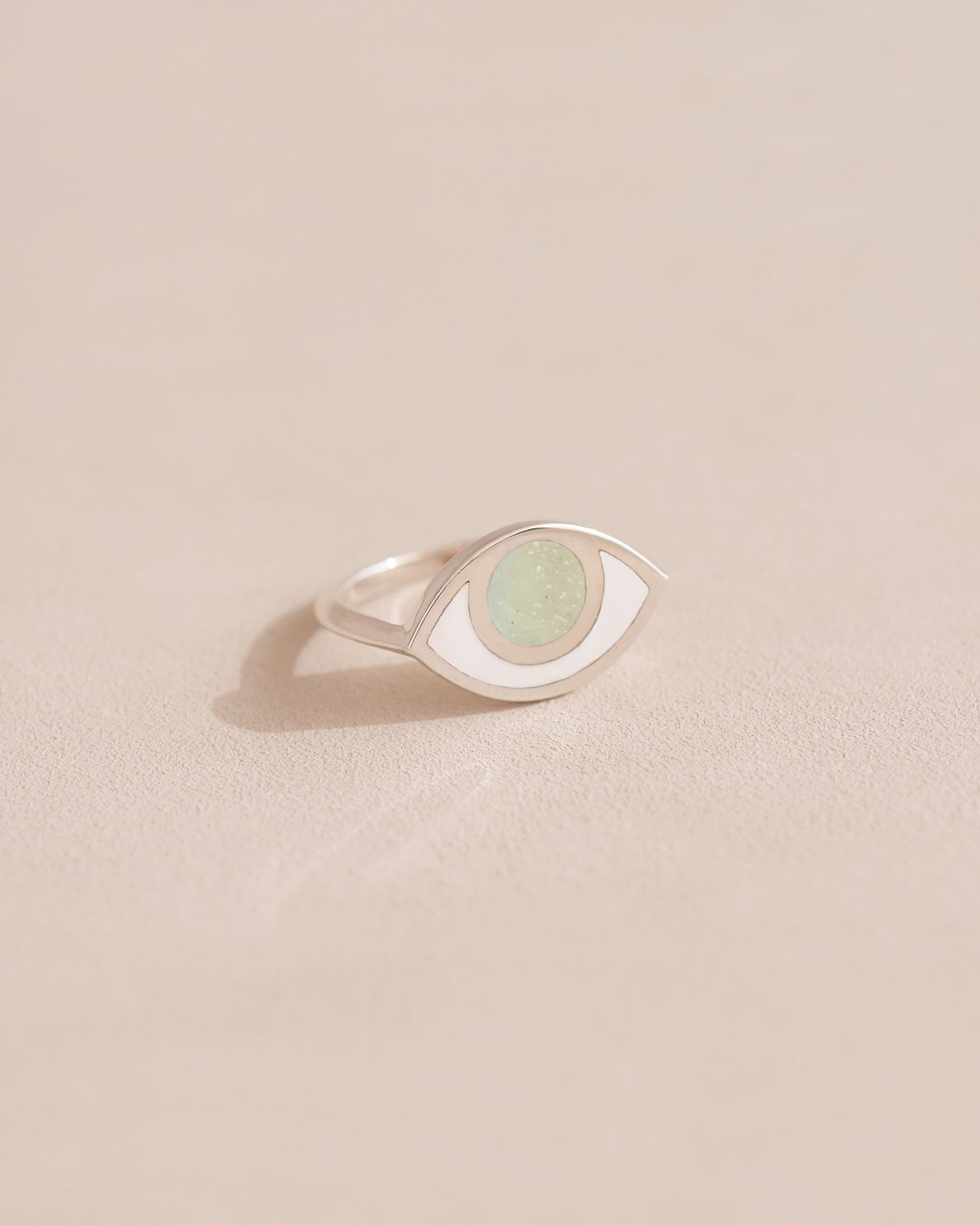 A silver ring with an opal center stone shaped like an eye, placed on a light background.