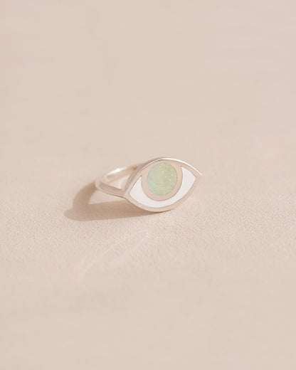 A silver ring with an opal center stone shaped like an eye, placed on a light background.