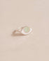 A silver ring with an opal center stone shaped like an eye, placed on a light background.