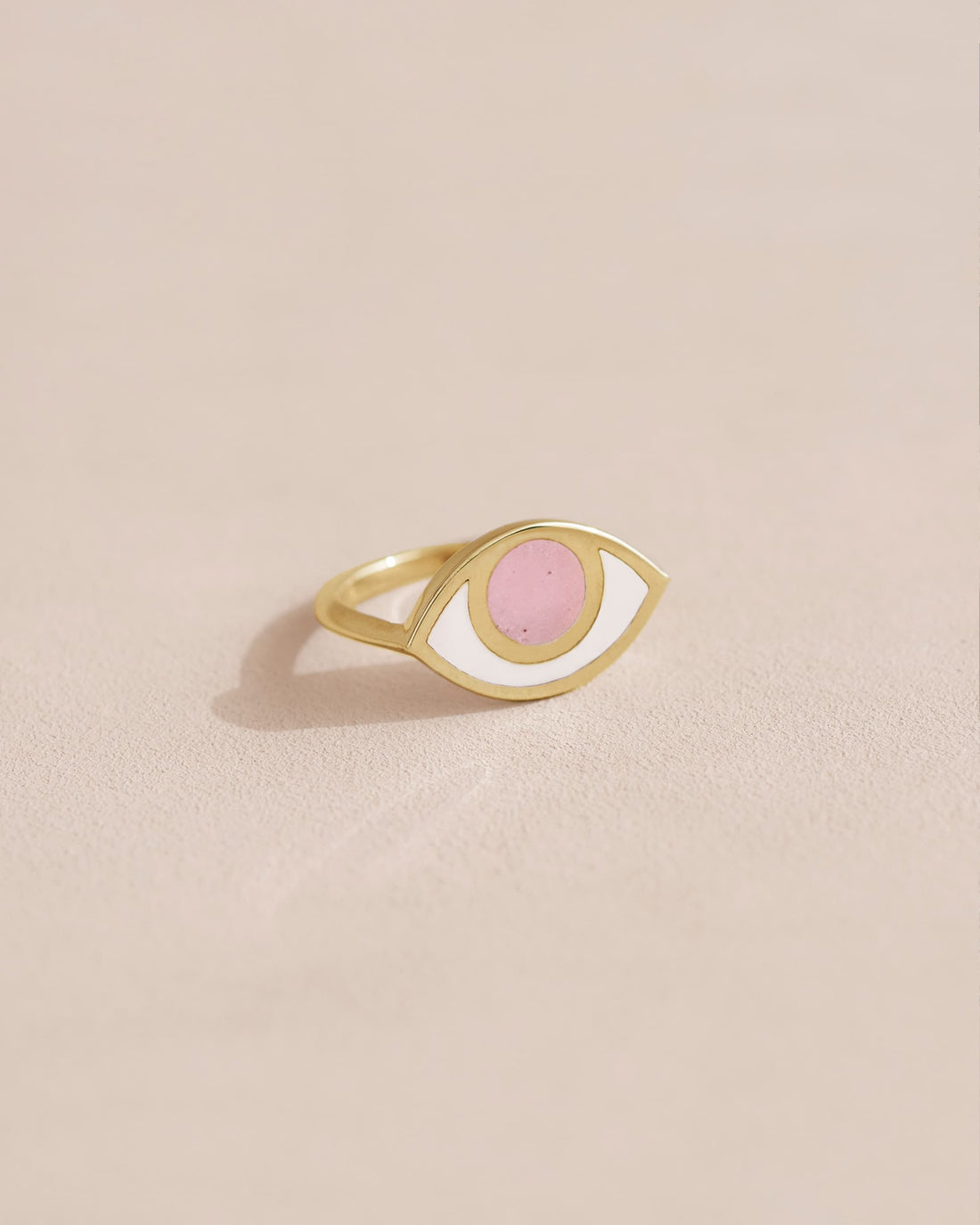 Gold ring with pink stone on a neutral background
