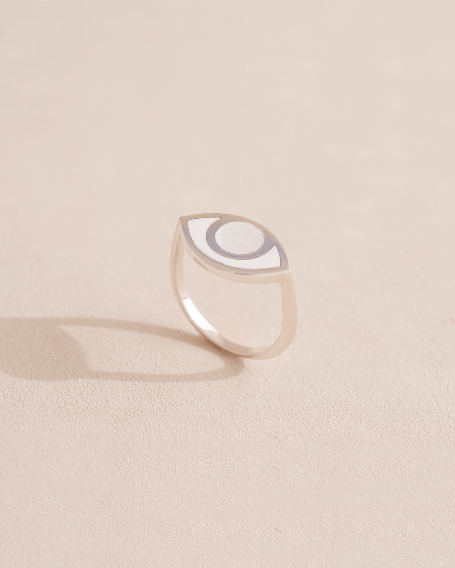 Silver ring with a half-moon design on a beige background