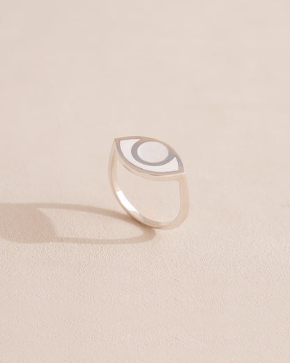 Silver ring with a half-moon design on a beige background