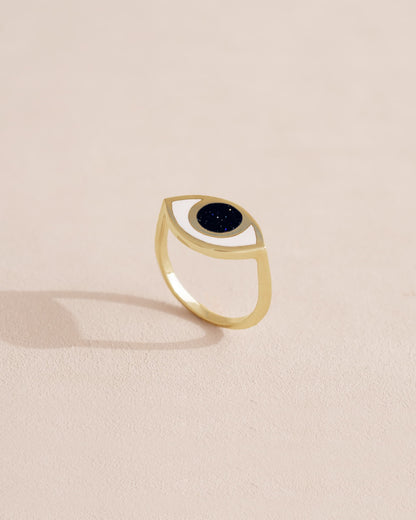 Gold ring with black stone on a light beige background