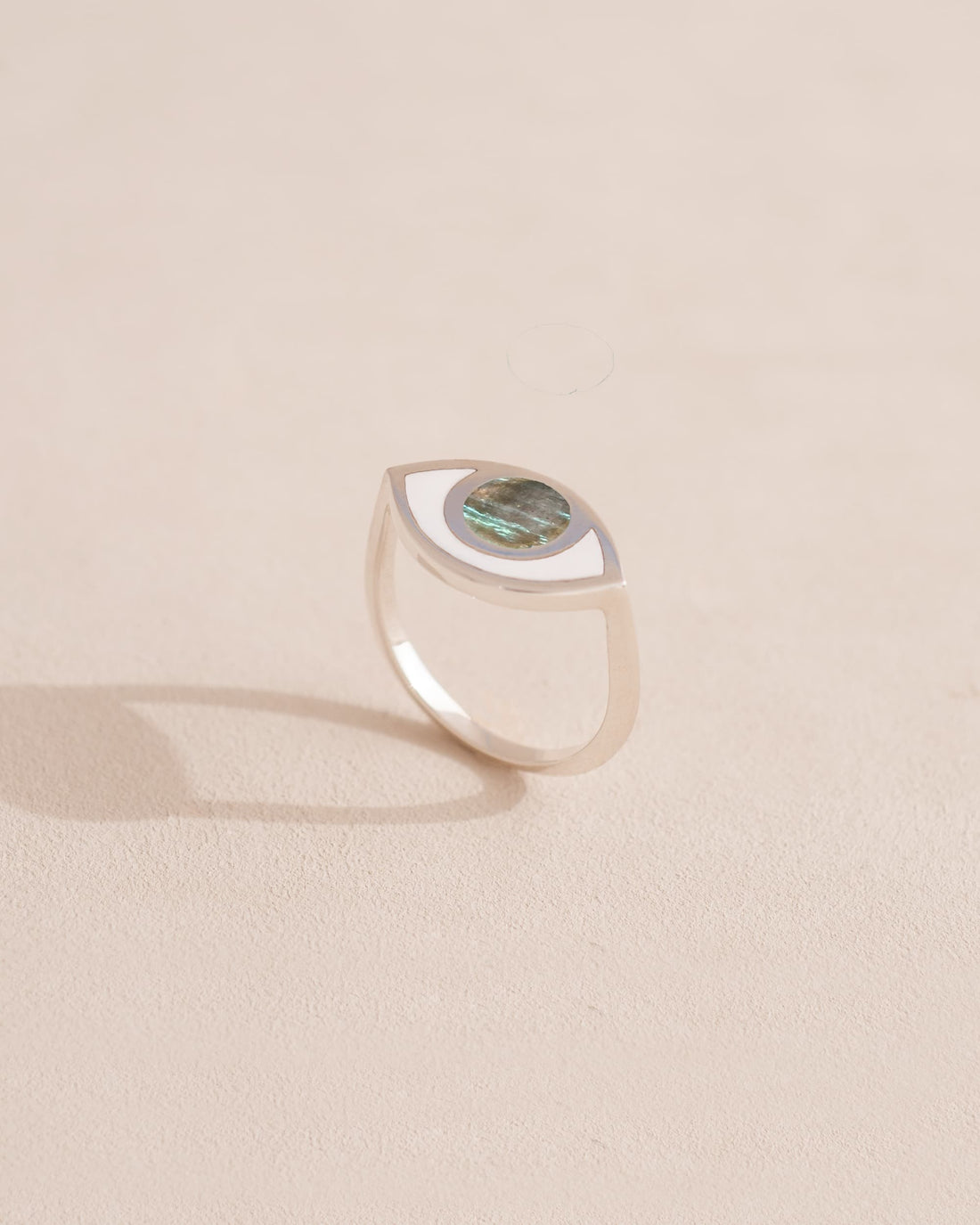 Silver ring with green gemstone on a light beige background
