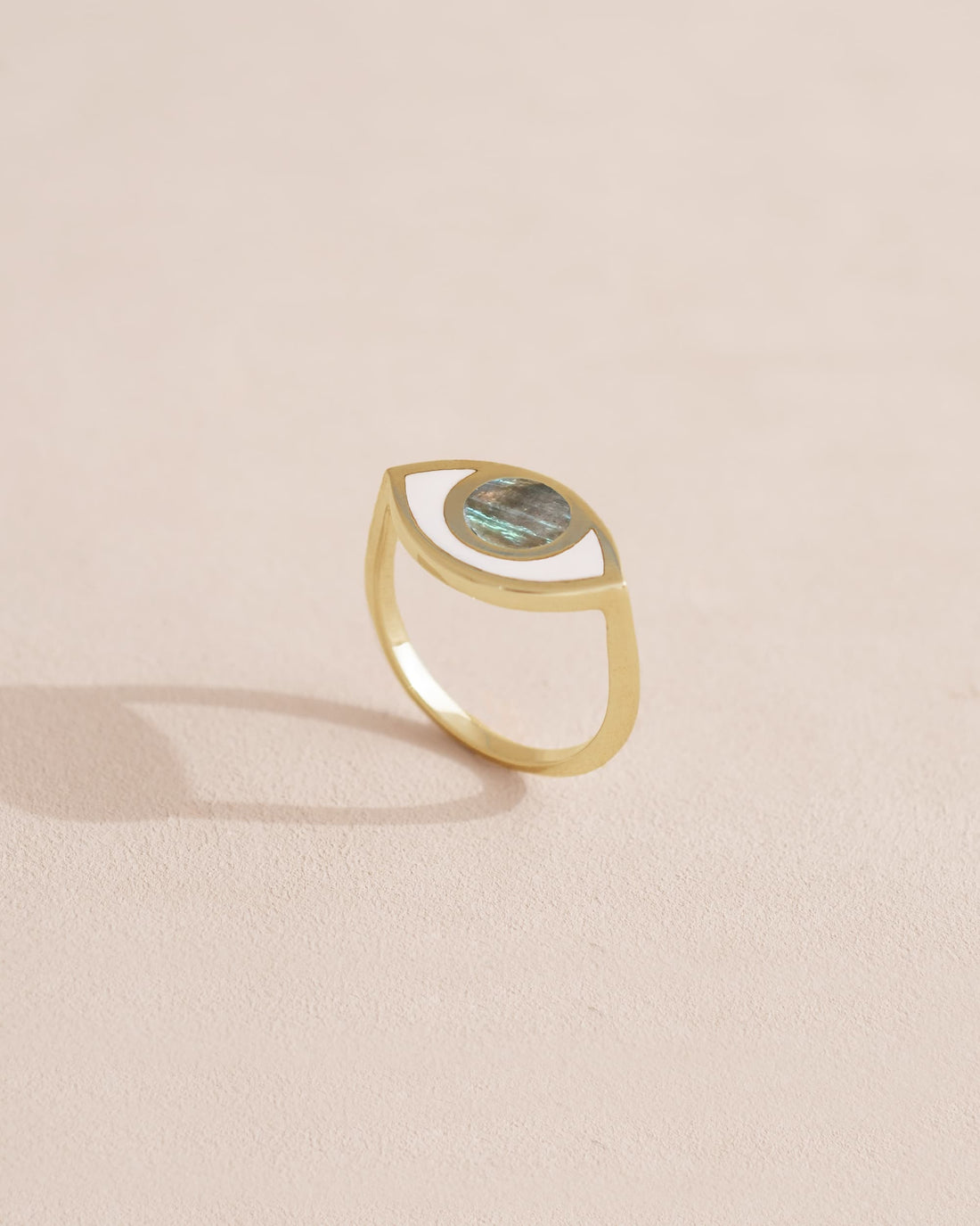 Gold ring with a green gemstone on a light beige background.