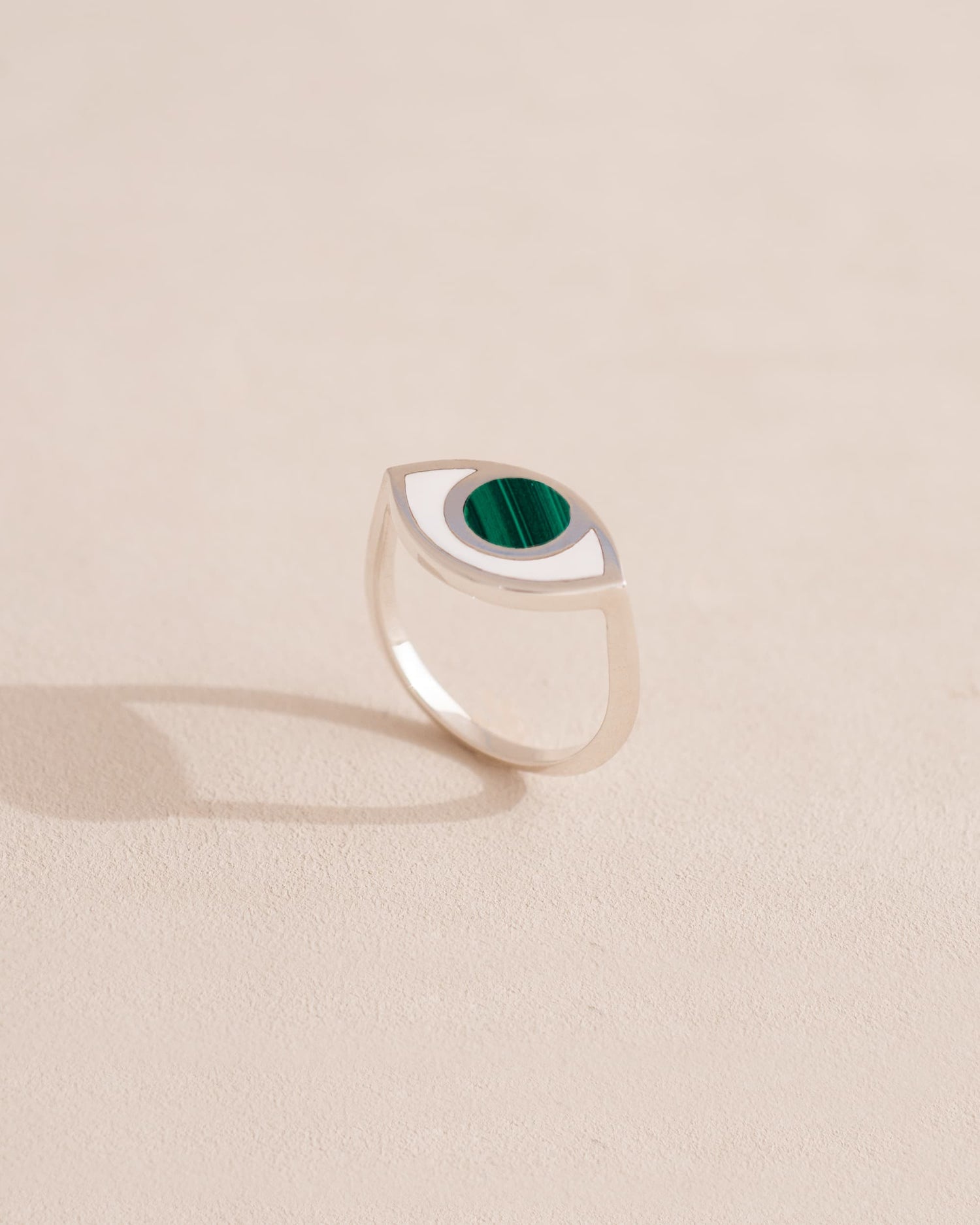Silver ring with green stone on a neutral background
