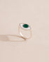 Silver ring with green stone on a neutral background