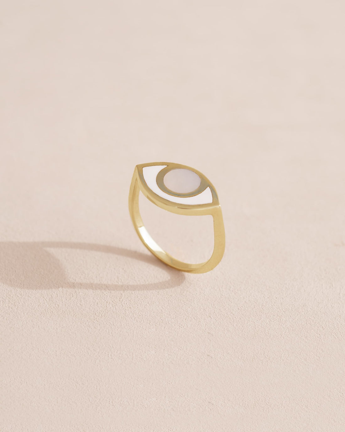 Gold ring with a half-moon design on a light beige background