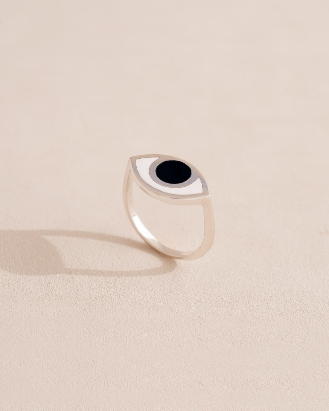 A silver ring with a onyx eyeshaped design on a beige background.