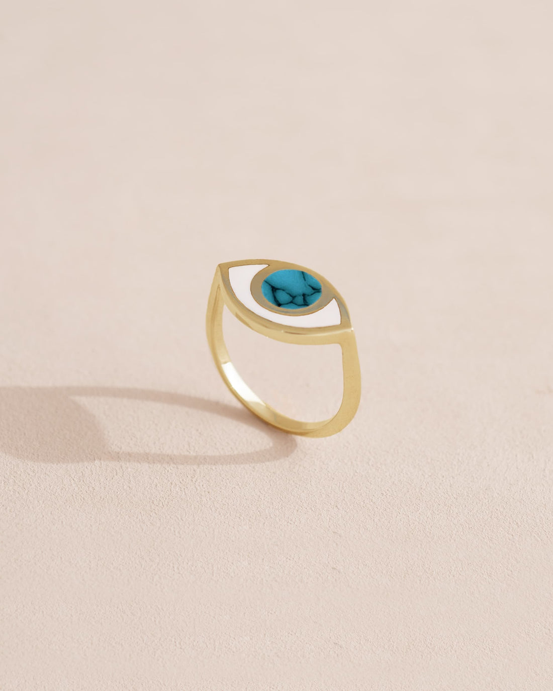 Gold ring with blue gemstone on a neutral background