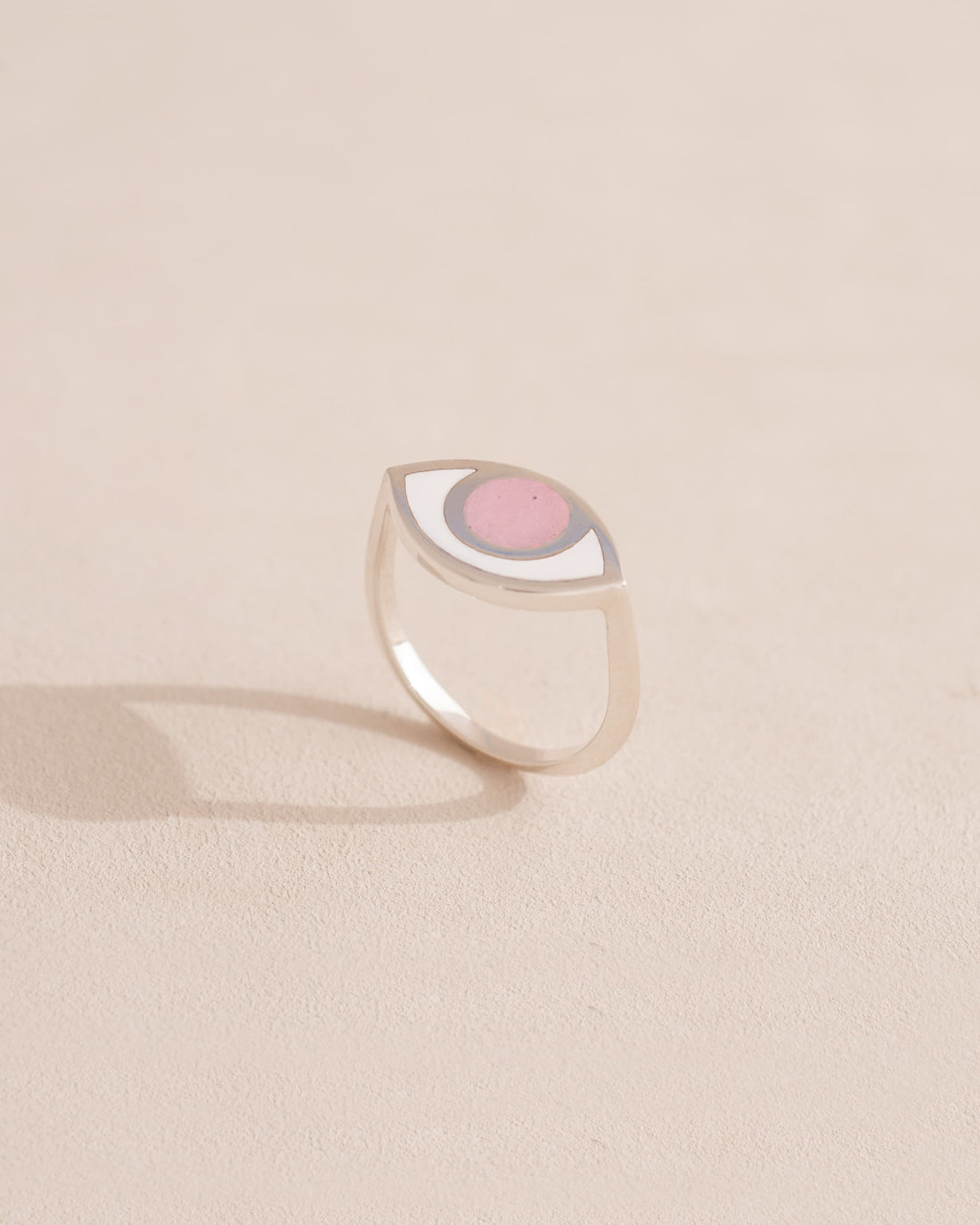 Silver ring with pink stone on a light beige background