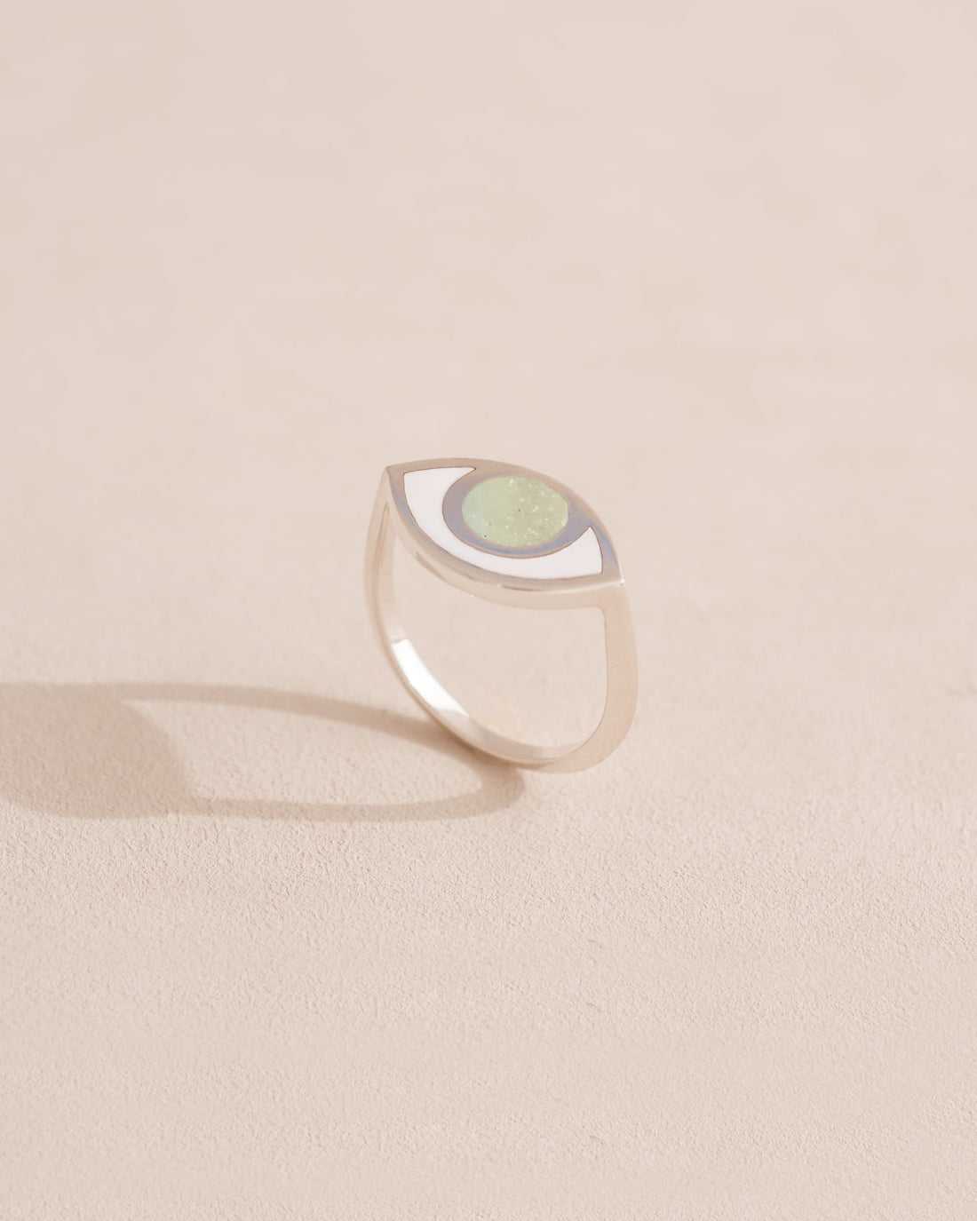 Silver ring with a green stone on a beige background